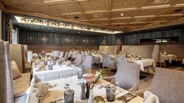 Ein elegantes Restaurant mit stilvoll gedeckten Tischen. Die Einrichtung besteht aus sanften Farben und gemütlichen Sitzgelegenheiten.