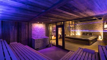 Ein luxuriöser Wellnessbereich mit Holzverkleidung und sanfter Beleuchtung. Die Sauna ist stilvoll eingerichtet und lädt zur Entspannung ein.
