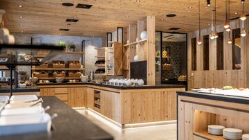 Moderne Küche mit Holzelementen und eleganter Beleuchtung. Der Raum ist offen und einladend, ideal für ein entspanntes Speiseerlebnis.