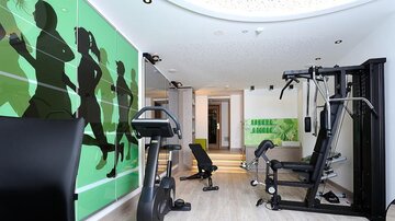Ein modernes Fitnessstudio mit verschiedenen Trainingsgeräten. Die Wände sind mit dynamischen Grafiken von Sportlern dekoriert.