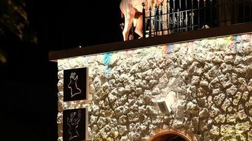 Ein außergewöhnliches Gebäude mit einer beleuchteten Steinfassade. Auf dem Dach steht eine beeindruckende Statue eines Ziegenbocks.