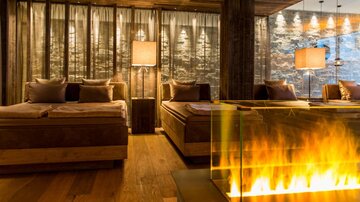 Ein stilvolles Wohnzimmer mit Holzmöbeln und sanfter Beleuchtung. Der moderne Kamin fügt eine gemütliche Atmosphäre hinzu.