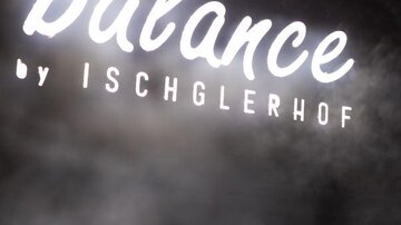 Ein kreatives Leuchtschild mit der Aufschrift "balance by ISCHGLERHOF". Der Hintergrund ist verschwommen, was eine entspannende Atmosphäre vermittelt.