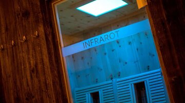 Eine moderne Infrarotsauna mit sanfter Beleuchtung. Der Schriftzug "INFRAROT" ist deutlich sichtbar.