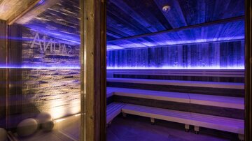 Eine moderne Sauna mit einer gemütlichen Atmosphäre. Sanfte blaue Beleuchtung und Holzoberflächen schaffen eine entspannende Umgebung.