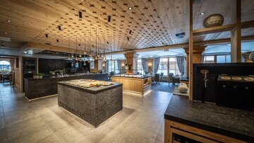 Ein elegantes Restaurant mit Holzdetails und modernen Möbeln. Die offene Küche und die ansprechende Einrichtung schaffen eine einladende Atmosphäre.