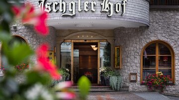 Das Bild zeigt den Eingang des Hotels "Ischgler Hof" mit einer einladenden Architektur. Bunte Blumenrahmen an der Vorderseite verleihen der Szene einen schönen Touch.