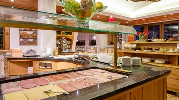 A beautiful buffet area with a selection of meats and cheeses. Fresh fruits and various dishes are available on the counter.