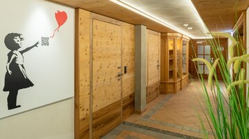 A hallway with wooden walls and shelves. On the wall hangs a piece of art of a girl holding a red balloon.