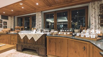 A cozy dining area with wooden cabinets and a buffet. The display is abundant and inviting, featuring various dishes and delicacies.