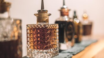 A series of elegant glass perfume bottles in various shapes and colors. The bottles stand on a dark background and exude a luxurious impression.