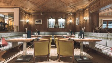 A cozy restaurant with wooden paneling and inviting seating areas. The tables are neatly set, creating a warm atmosphere.