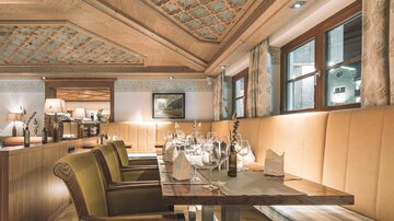 An elegant restaurant with stylish wooden furniture and beautifully decorated interior. The tables are set for guests and offer a cozy atmosphere.