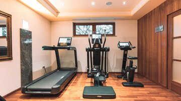 A modern gym with a treadmill, an elliptical trainer, and a stationary bike. The walls are in neutral colors, and the lighting is bright and inviting.