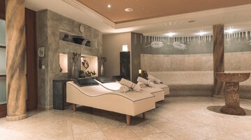 An elegant wellness area with stylish loungers and gentle lighting. The walls are painted in neutral tones, creating a relaxing atmosphere.