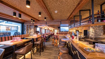 Ein modernes Restaurant mit Holzdekor und gemütlichen Sitzplätzen. Die Atmosphäre ist warm und einladend, ideal für ein entspanntes Essen.