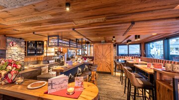 Ein gemütliches Restaurant mit Holzinterieur und gutem Ambiente. Die Bar und Tische laden zum Entspannen ein.