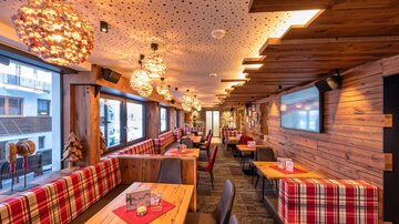 Ein gemütliches Restaurant mit Holzwänden und modernen Lampen. Die Tische sind hübsch gedeckt und bieten Platz für Gäste.
