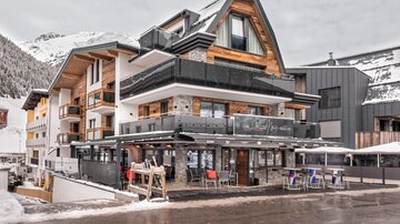 Ein modernes Hotelgebäude in einer winterlichen Landschaft. Schnee bedeckt die Umgebung, und die Architektur kombiniert Holz und moderne Elemente.