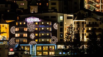 Ein Gebäude mit leuchtenden Weihnachtsdekorationen in einer städtischen Umgebung bei Nacht. Der Name "Solaria" ist gut sichtbar und die Atmosphäre wirkt festlich.