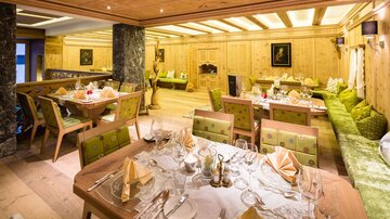 Ein gemütliches Restaurant mit Holzinterieur und eleganten Tischgedecken. Die Atmosphäre ist warm und einladend, ideal für ein besonderes Essen.