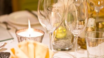 Ein elegant gedeckter Tisch mit Gläsern und einem Kerzenlicht. Die Serviette ist kunstvoll gefaltet und sorgt für eine festliche Atmosphäre.