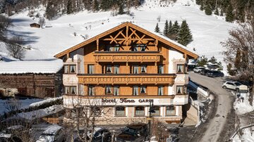 Ein charmantes Hotel im Alpenstil, umgeben von schneebedeckten Bäumen. Die Fassade ist aus Holz mit einem einladenden Eingangsbereich.