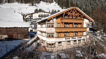 Ein charmantes Hotel inmitten einer verschneiten Winterlandschaft. Umgeben von Bergen und traditioneller Architektur bietet es eine gemütliche Atmosphäre.