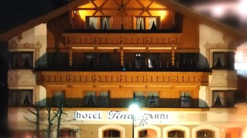 Ein charmantes Hotel mit Holzfassade, beleuchtet in der Nacht. Die Balkone und Fenster verleihen dem Gebäude eine einladende Atmosphäre.