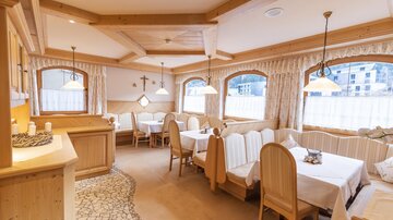 Ein gemütliches Restaurant mit Holzdekor und hellen Tischen. Das Licht scheint durch die Fenster und schafft eine einladende Atmosphäre.