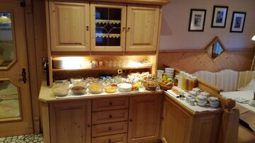 Ein geschmackvoll eingerichteter Raum mit einem großen Buffet. Das Buffet enthält eine Auswahl an Frühstücksartikeln wie Obst, Joghurt und Getränke.