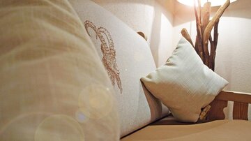 Ein gemütliches Sofa mit dekorativen Kissen. Neben dem Sofa steht eine Lampe aus Holz.