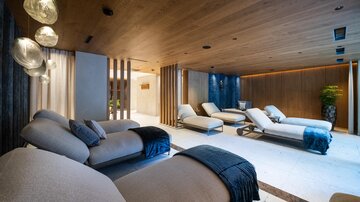Ein eleganter Wellnessbereich mit bequemen Liegen und warmem Holzdekor. Sanfte Beleuchtung schafft eine entspannende Atmosphäre.