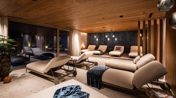 Ein stilvolles Wellness-Zimmer mit bequemen Liegen und warmem Holz. Sanfte Beleuchtung schafft eine entspannende Atmosphäre.