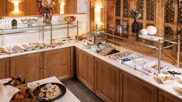 Ein schönes Buffet mit einer Vielzahl von Speisen in einer gemütlichen Holz-Einrichtung. Die Tische sind liebevoll gedeckt und laden zum Schlemmen ein.