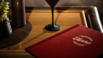 Ein eleganter Cocktail auf einem Tisch. Im Hintergrund ist eine stilvolle Atmosphäre mit sanfter Beleuchtung.