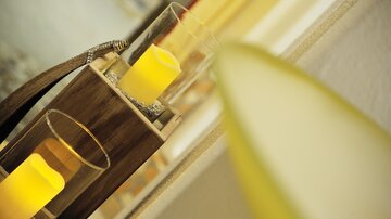 A decorative candle holder with yellow candles in glass containers. Blurred colors can be seen in the background, creating a cozy atmosphere.
