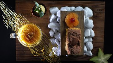 An appealing dessert on a wooden board, along with a cup of drink. The arrangement consists of various ingredients and decorations that enrich the dish.