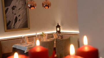 A stylish restaurant with soft lighting and a cozy atmosphere. Red candles and decorative elements create an inviting ambiance.