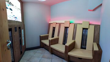 A relaxing space with three comfortable seats and modern lighting. The walls are simple and the atmosphere is calming.