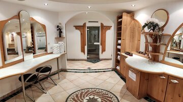 A stylish hair salon with bright wooden shelves and large mirrors. The room has an inviting atmosphere and is clean and well-organized.