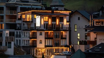A modern building in a picturesque mountain landscape. The windows are illuminated, creating an inviting atmosphere.