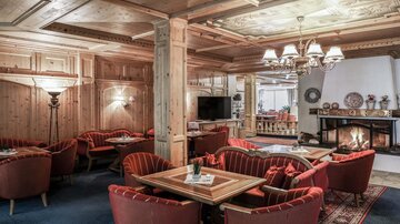 Eine gemütliche Lounge mit Holzwänden und roten Sesseln. Der Kamin sorgt für eine angenehme Atmosphäre.