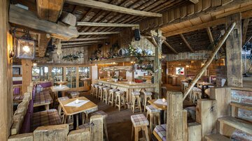 Ein gemütliches Restaurant mit Holzinterieur und rustikalem Charme. Die Sitzgelegenheiten und Dekoration schaffen eine einladende Atmosphäre.