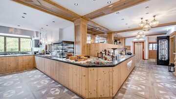 Eine moderne Küche mit Holzverkleidung und einer großen Theke. Der Raum ist hell und einladend, ideal für gemeinsames Kochen und Essen.
