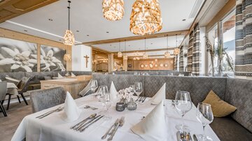 Ein elegantes Restaurant mit stilvollen Lampen und einer gemütlichen Atmosphäre. Tische sind mit weißen Tischdecken und feinem Geschirr gedeckt.