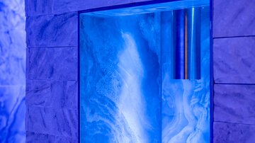 Ein moderner Wandbereich mit beleuchtetem, blauem Panel. Der Stein sorgt für eine elegante Atmosphäre.