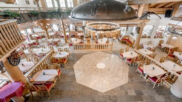 Ein gemütliches Restaurant mit Holzdekor und vielen Tischen. Die entspannte Atmosphäre wird durch große Fenster und elegantes Licht ergänzt.