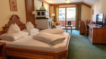 Ein gemütliches Hotelzimmer mit zwei Betten, einer schönen Holzverkleidung und einem Balkon. Das Zimmer ist hell und freundlich eingerichtet.