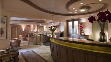 Ein eleganter Empfangsbereich mit Holzdekor und gemütlicher Beleuchtung. Blumenarrangements und eine einladende Bar schaffen eine angenehme Atmosphäre.